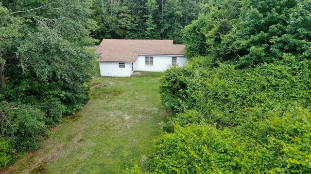 an aerial view of a house with yard and trees all around
