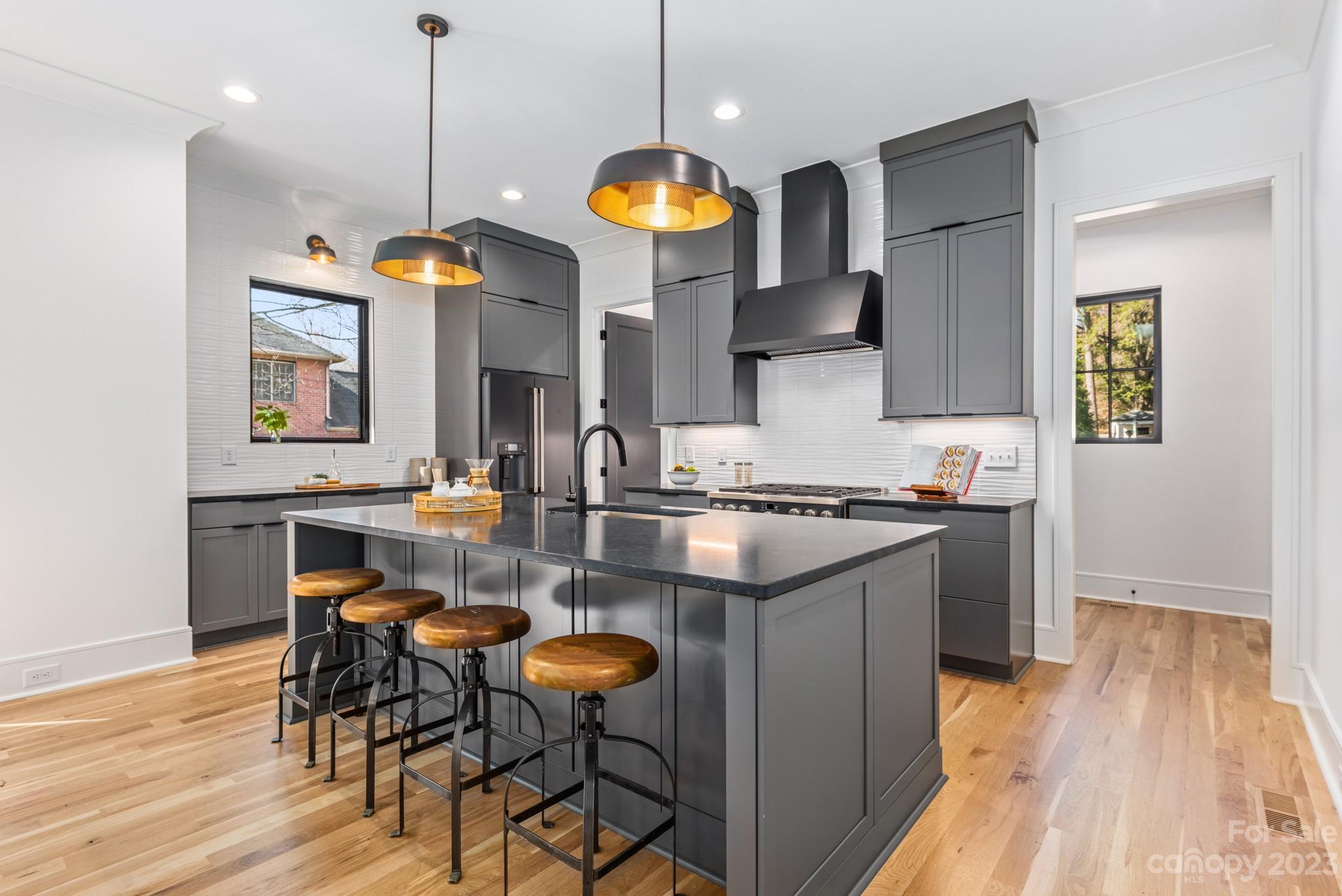 4338 Castleton Road Charlotte, NC 28211 - Photo 9 of 38 a kitchen with stainless steel appliances granite countertop a stove a refrigerator a sink a dining table and chairs with wooden floor