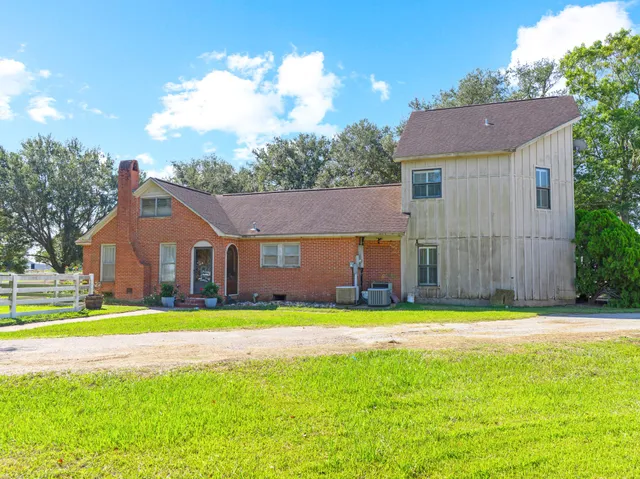a view of a house with a big yard and large trees