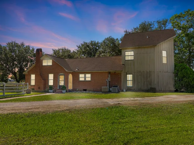 a view of a big house with a big yard and large trees