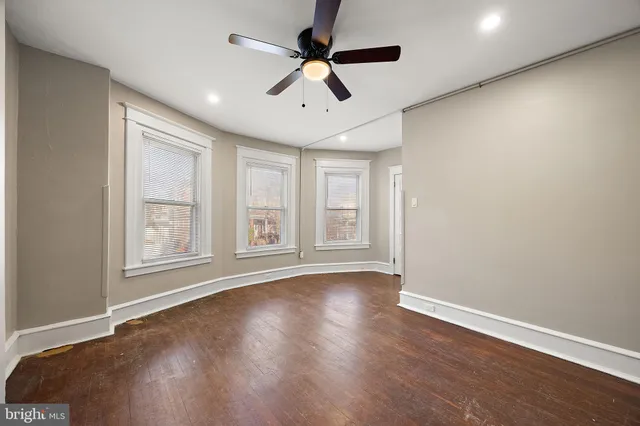 a view of an empty room with a window and wooden floor