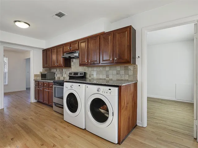 a kitchen with granite countertop a sink a stove top oven and wooden cabinetry