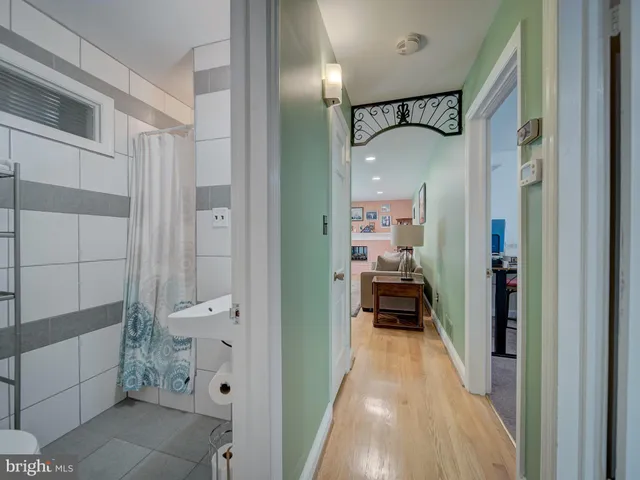 a view of a hallway with wooden floor and a bathroom