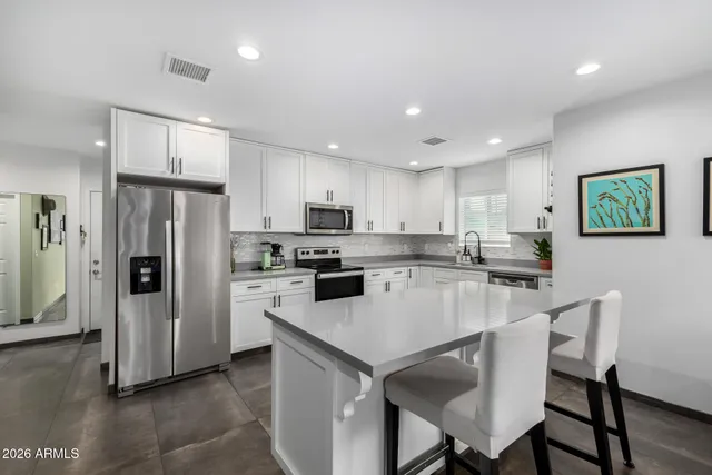 a kitchen with a refrigerator a stove a dining table and chairs