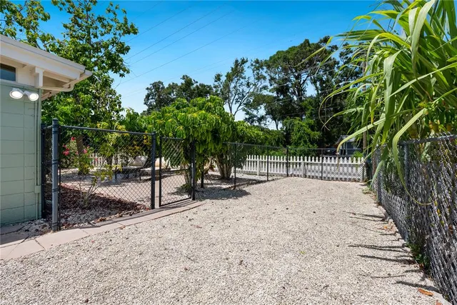 a view of a backyard with large trees and wooden fence