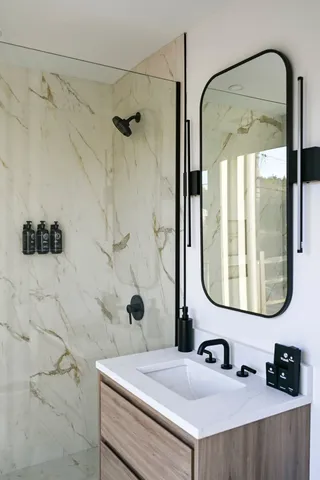 a bathroom with a sink vanity mirror and shower