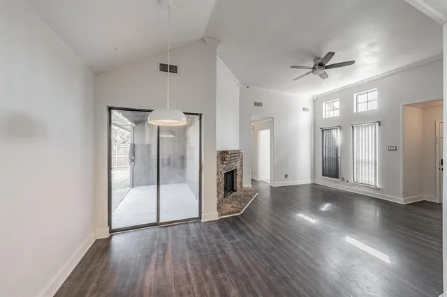 an empty room with wooden floor a ceiling fan and windows