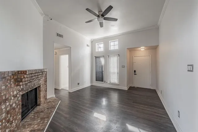 a view of an empty room with wooden floor and a fireplace