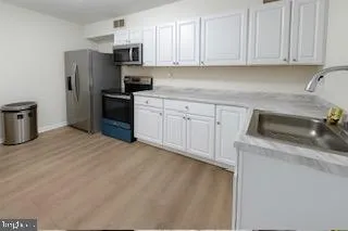 a kitchen with white cabinets and wooden floor