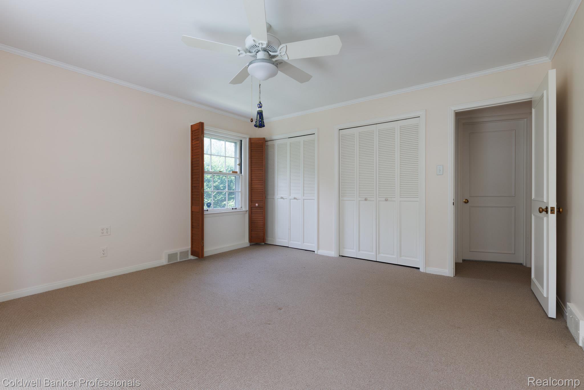 1018 Harvard Road Grosse Pointe, MI 48230 - Photo 19 of 40 Carpeted room featuring a ceiling fan with light fixture, window with wood shutters, and two sets of bi-fold closet doors
