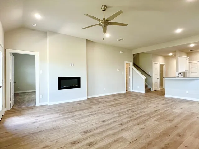 an empty room with wooden floor and a ceiling fan