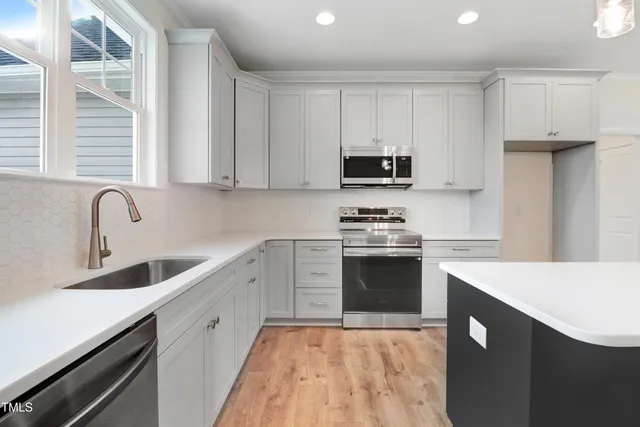 a kitchen with kitchen island white cabinets appliances and a window