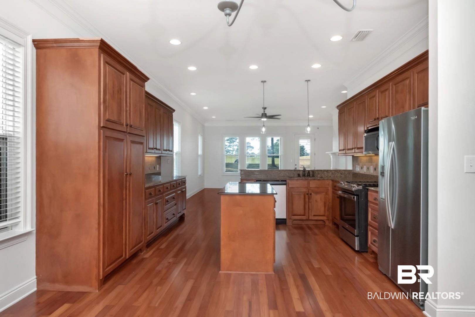30585 Pine Court Daphne, AL 36527 - Photo 32 of 49 Kitchen featuring ornamental molding, a peninsula, brown cabinetry, dark stone counters, and stainless steel appliances