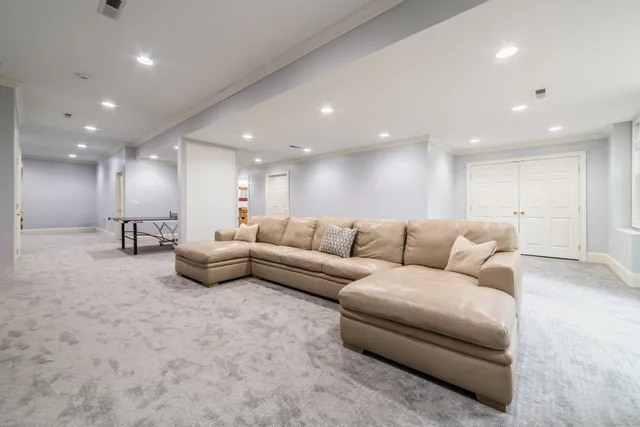 a living room with furniture and a white wall with kitchen view
