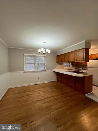 a view of a kitchen with kitchen island a sink wooden floor and a refrigerator