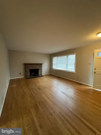 a view of empty room with wooden floor and fireplace