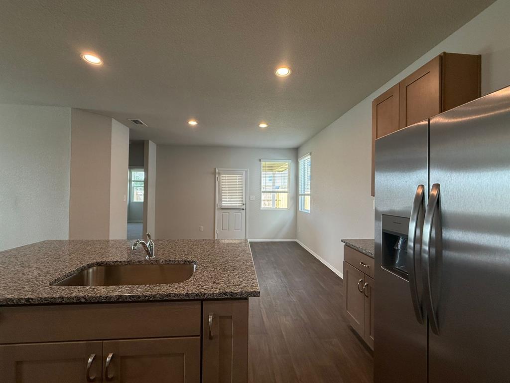 2707 Totley Road Pflugerville, TX 78660 - Photo 11 of 39 Kitchen with stainless steel fridge with ice dispenser, dark stone countertops, recessed lighting, dark wood finished floors, and a textured ceiling
