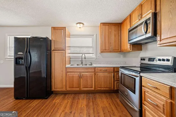 an empty room with a chandelier fan and wooden floor