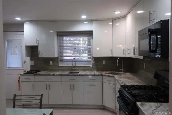 a kitchen with granite countertop a sink a stove and cabinets