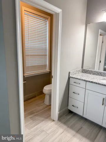 a bathroom with a granite countertop sink toilet and mirror