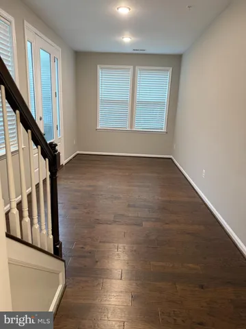 a view of an empty room with wooden floor and next to a window