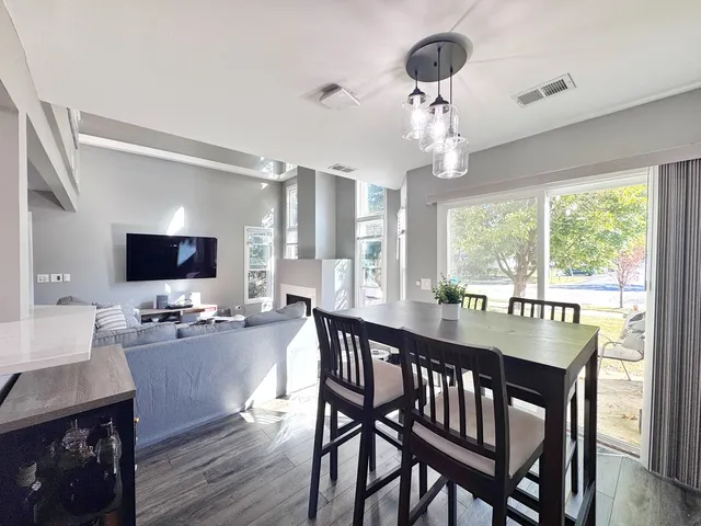 a dining room with wooden floor a chandelier a wooden table and chairs