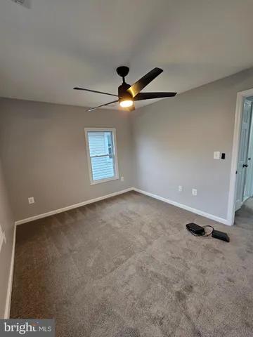 an empty room with a ceiling fan and window