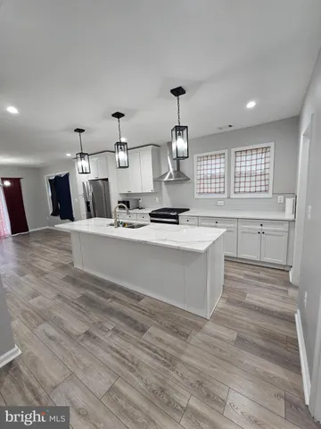 a large white kitchen with kitchen island a sink stainless steel appliances and cabinets