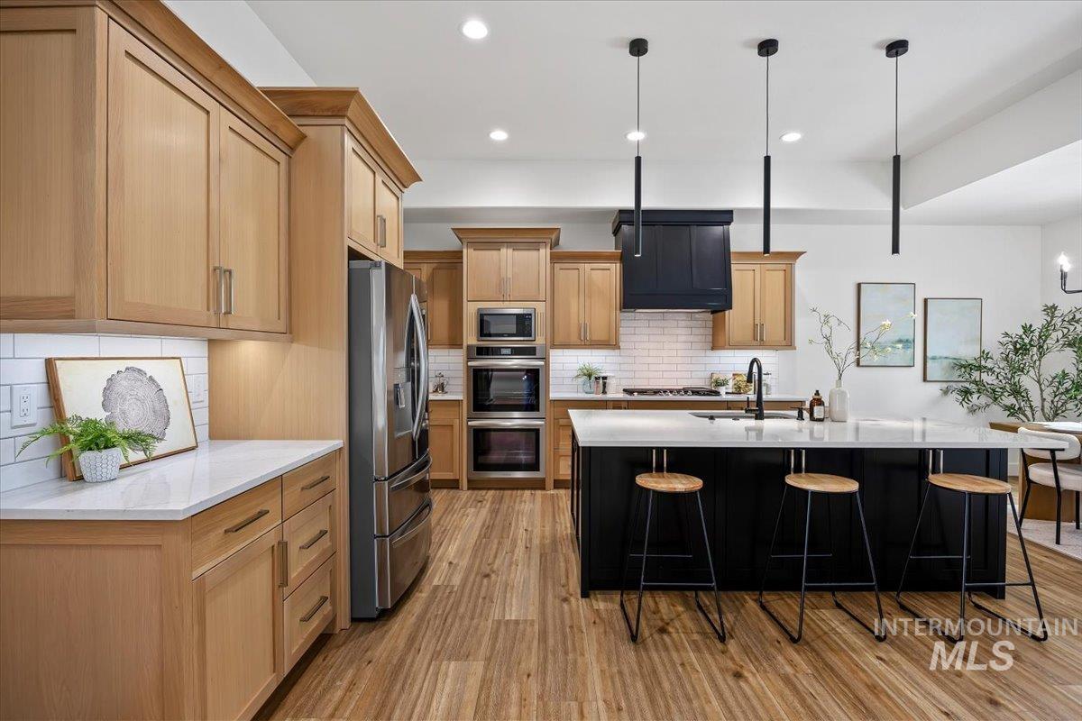924 Trapper Peak Road Kimberly, ID 83341 - Photo 15 of 40 Kitchen featuring light stone countertops, stainless steel appliances, pendant lighting, light wood-style flooring, and two tone cabinets