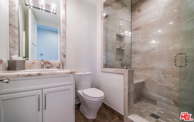 a bathroom with a granite countertop sink toilet a mirror and shower