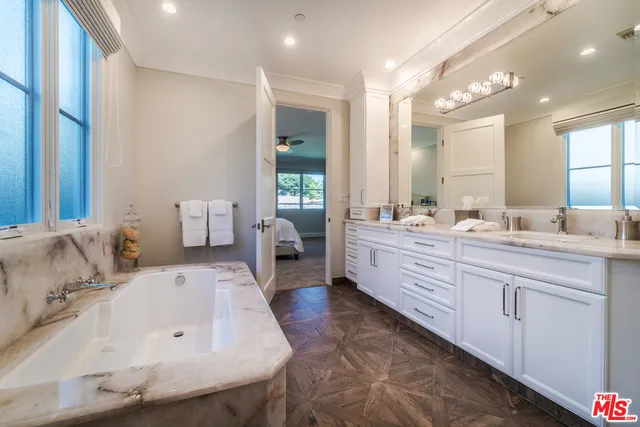 a spacious bathroom with a double vanity sink mirror and bathtub