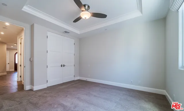 an empty room with a ceiling fan and carpet