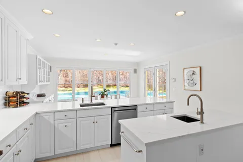 a kitchen with white cabinets a sink appliances and a counter top space