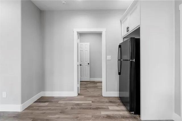 a view of an empty room with wooden floor and closet