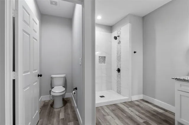a bathroom with a granite countertop toilet a sink and shower