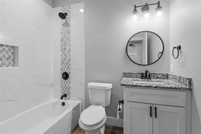 a bathroom with a granite countertop sink a toilet and a mirror
