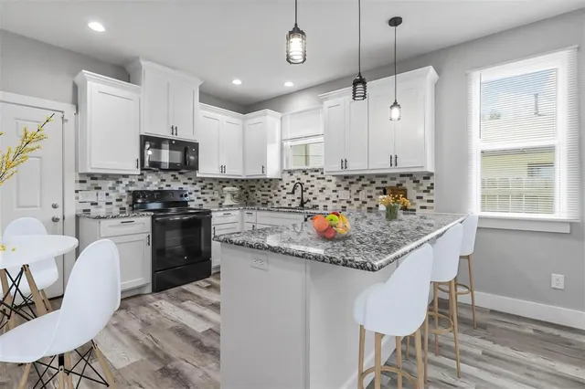 a kitchen with stainless steel appliances granite countertop a stove a sink a microwave a refrigerator and cabinets