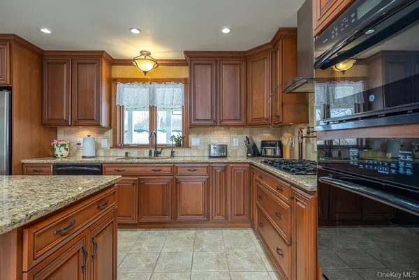 a kitchen with stainless steel appliances granite countertop a sink a stove counter space and cabinets