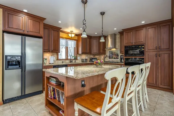 a kitchen with stainless steel appliances granite countertop a refrigerator a stove a sink a dining table and chairs