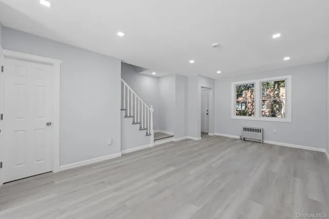 a view of an empty room with wooden floor and window