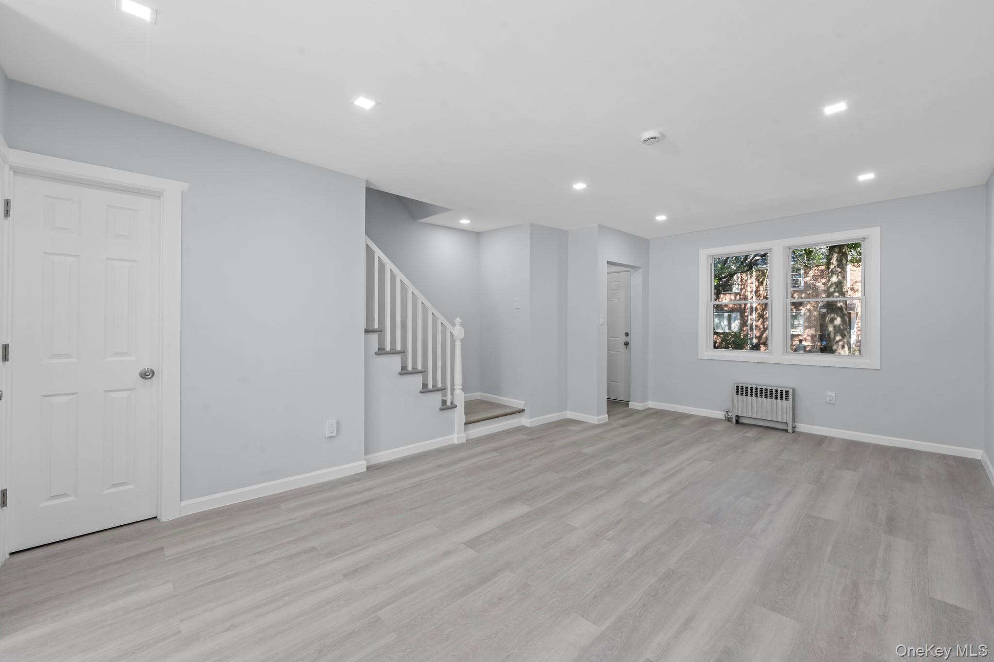 110-08 172nd Street Queens, NY 11433 - Photo 3 of 15 a view of an empty room with wooden floor and window