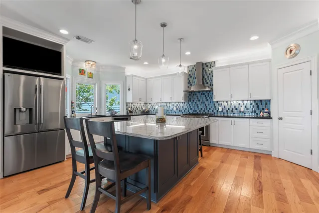 a kitchen with stainless steel appliances granite countertop a sink a stove a refrigerator and island with wooden floor