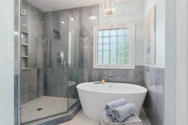 a bathroom with a tub shower sink and mirror