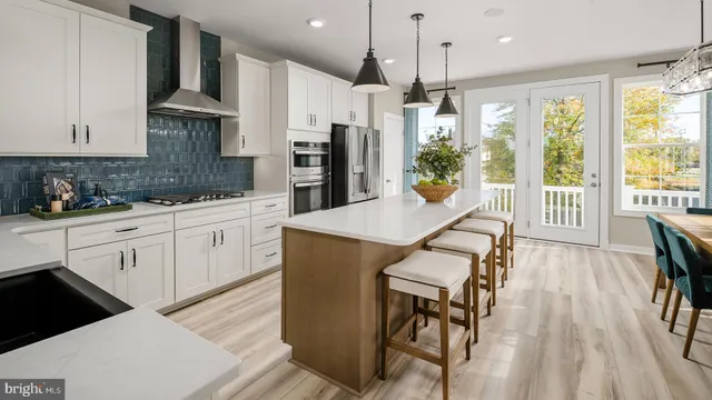 a kitchen with stainless steel appliances kitchen island granite countertop a table chairs in it and white cabinets