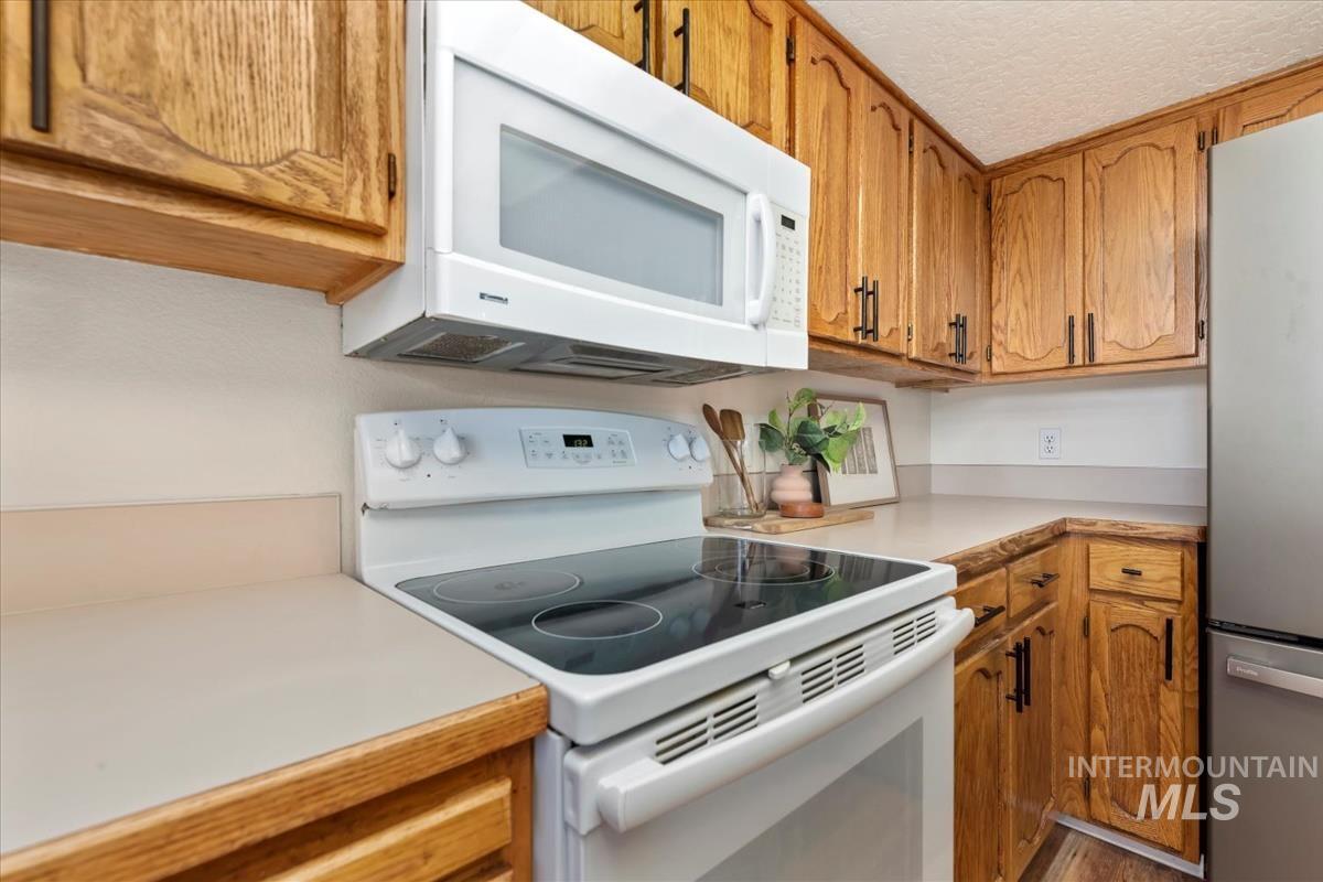685 South Winthrop Way Boise, ID 83709 - Photo 13 of 46 Kitchen featuring white appliances, light countertops, brown cabinetry, and a textured ceiling