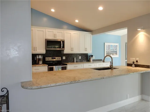 a kitchen with granite countertop a stove a sink a microwave and a refrigerator