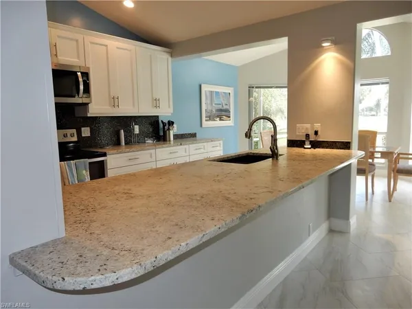 a view of a kitchen with kitchen island a sink a stove and wooden floors