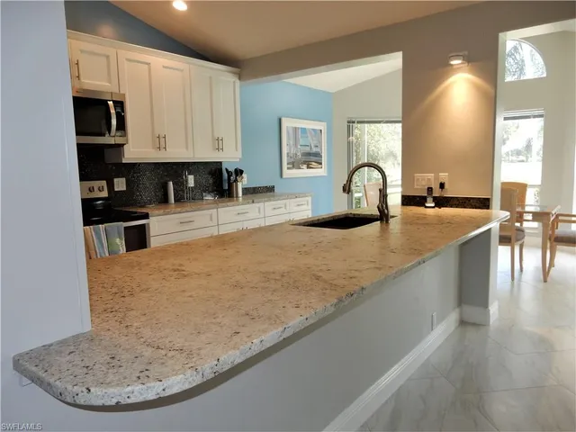 a view of a kitchen with kitchen island a sink a stove and wooden floors