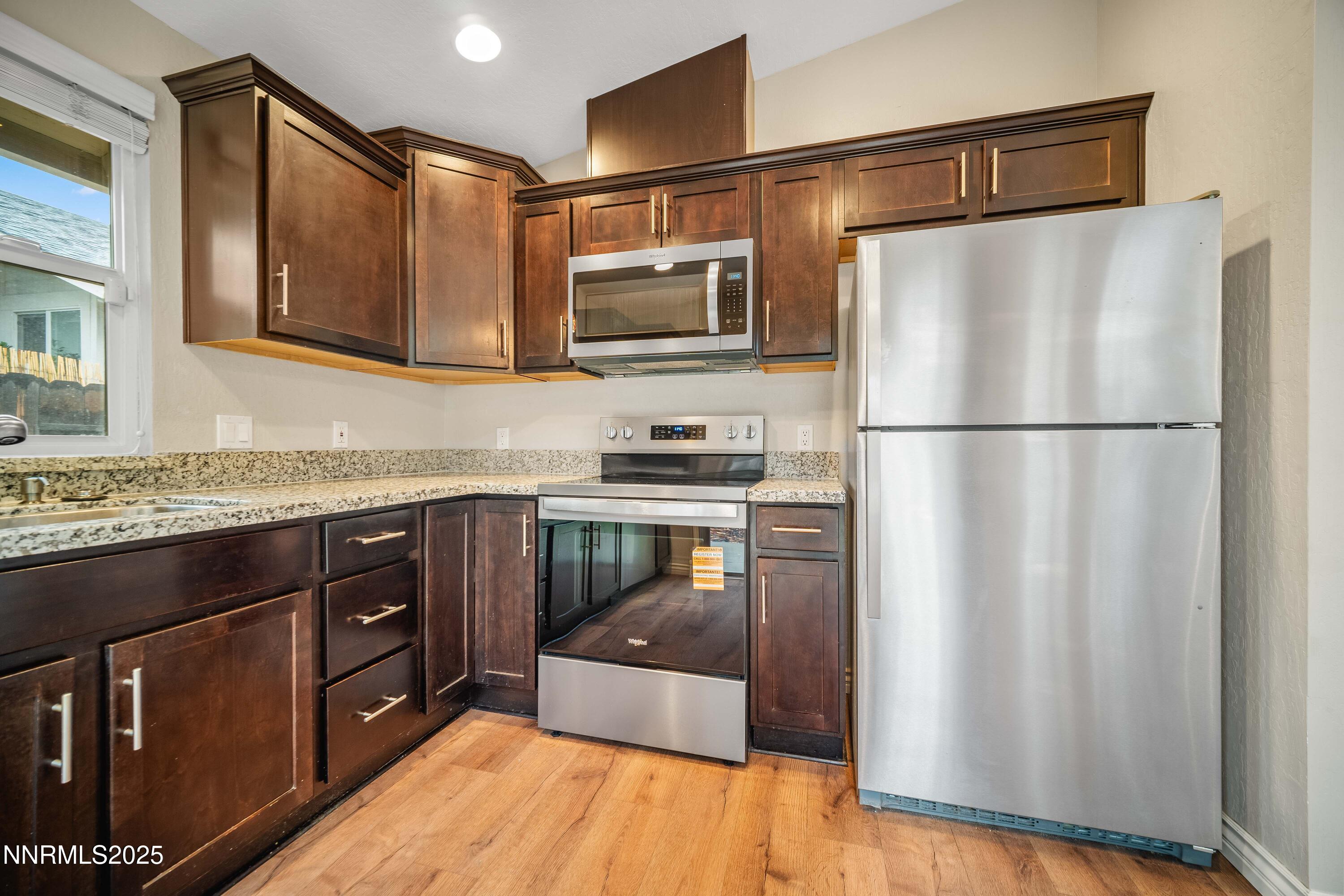 1146 Ambassador Drive Reno, NV 89523 - Photo 7 of 23 a kitchen with granite countertop a refrigerator a stove a sink and a microwave