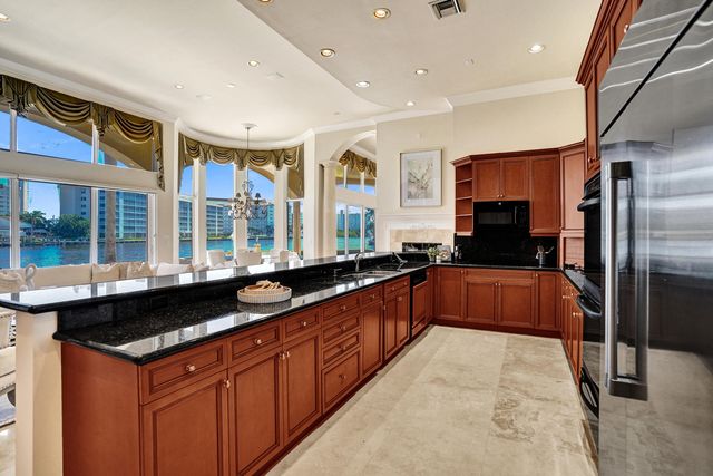 a large kitchen with stainless steel appliances granite countertop a sink and a refrigerator